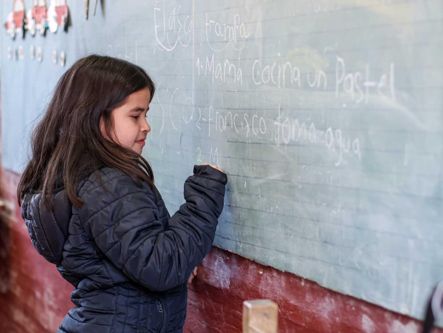 Niña de unos 9 años, escribiendo en la pizarra de su aula