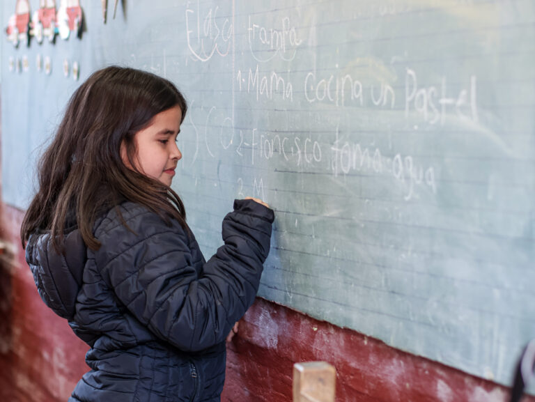 Niña de unos 9 años, escribiendo en la pizarra de su aula